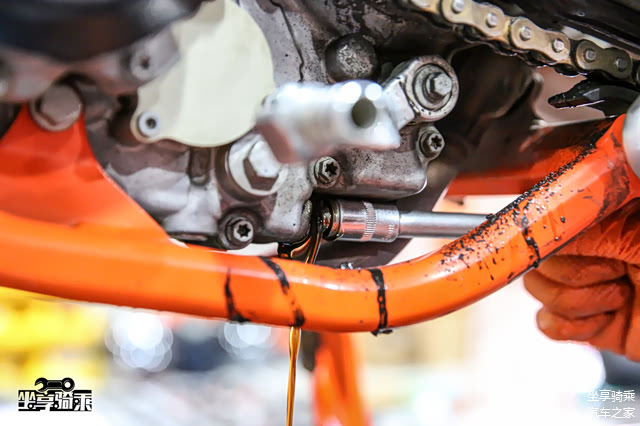 拆除发动机护板后拧开放油螺栓，放掉旧机油